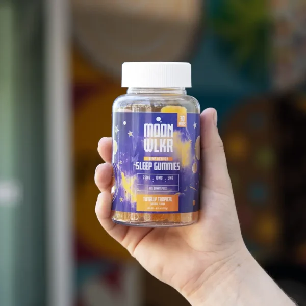 Hand holding a bottle of Moonwlkr sleep gummies, designed to support sleep and relaxation. These cannabinoid-infused gummies offer a natural sleep aid solution for restful nights