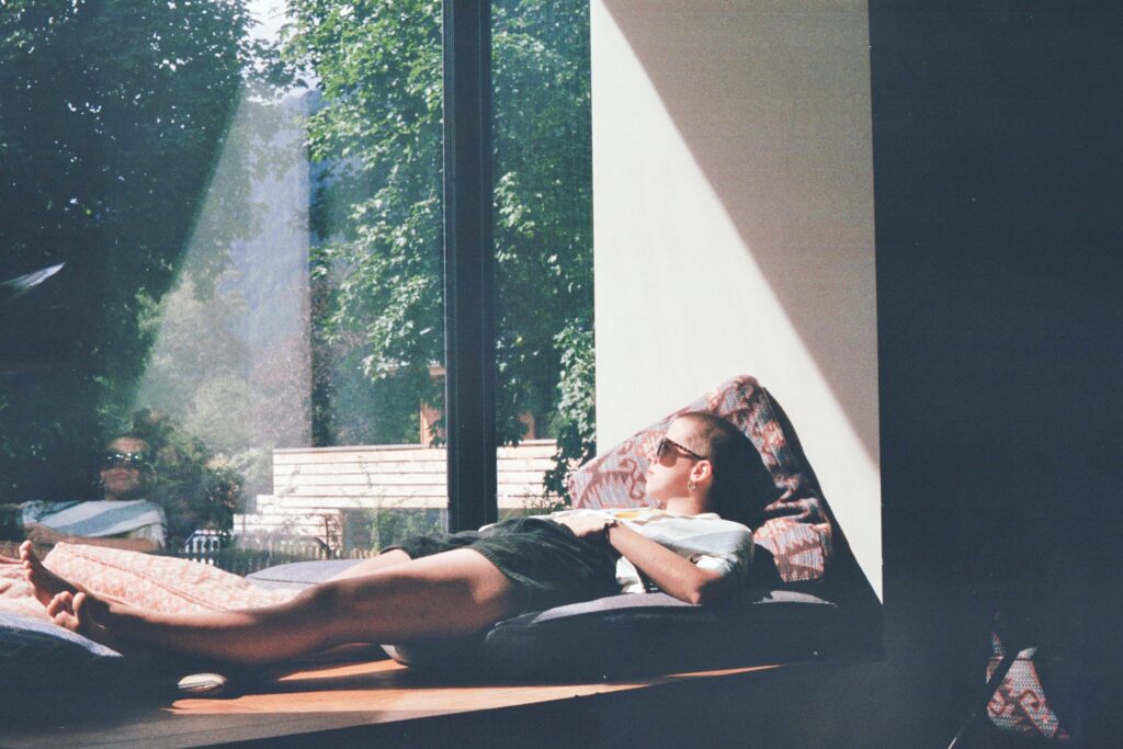 Woman laying on a bench looking out the window