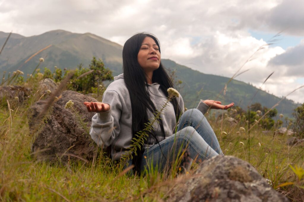 Woman sitting out in the foothills of nature with her palms up 