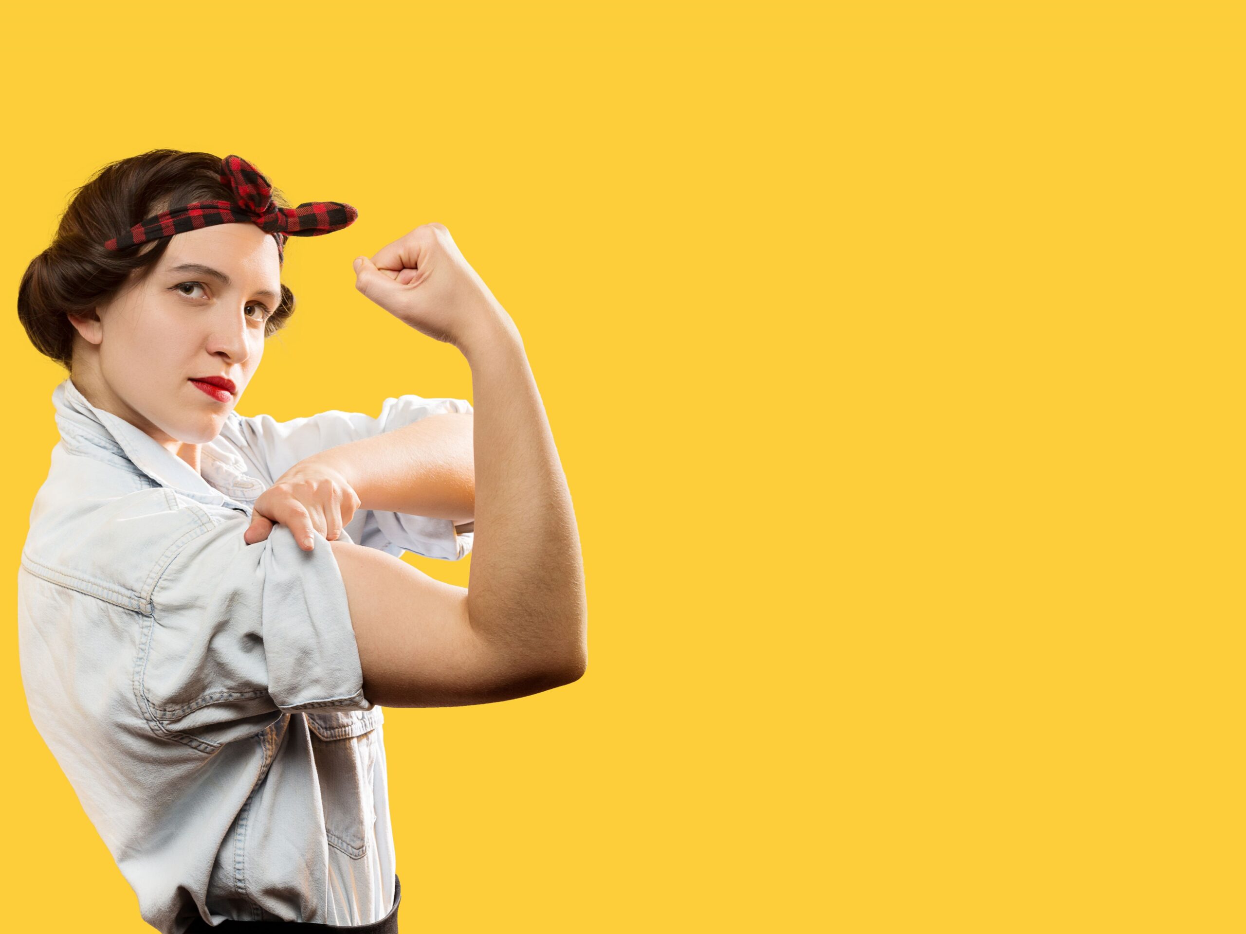 Woman wearing a red bandana and flexing her bicep muscle